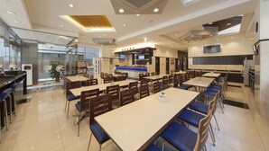 Un restaurante moderno con varias mesas y sillas, una zona de cocina y un área de asientos con mostrador.
