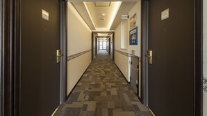 Pasillo de hotel con pisos alfombrados, puertas dobles y un letrero que indica la habitación 1304.