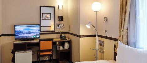 A hotel room with a bed, desk, chair, television, and a small refrigerator.
