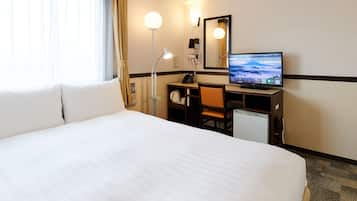 Habitación de hotel con una cama grande, un escritorio con computadora, una lámpara de escritorio, un teléfono y un espejo.