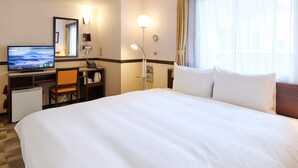 A hotel room with a bed, desk, chair, television, and a window with curtains.