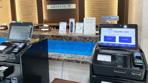 A hotel reception desk with digital displays, a cashless payment option, and a sign indicating a 5% discount.