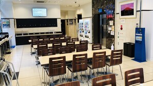 A conference room with tables and chairs, a projector screen, vending machines, and a cinema sign. - Toyoko Inn Tokyo Hachioji Station Kita (Hachioji)