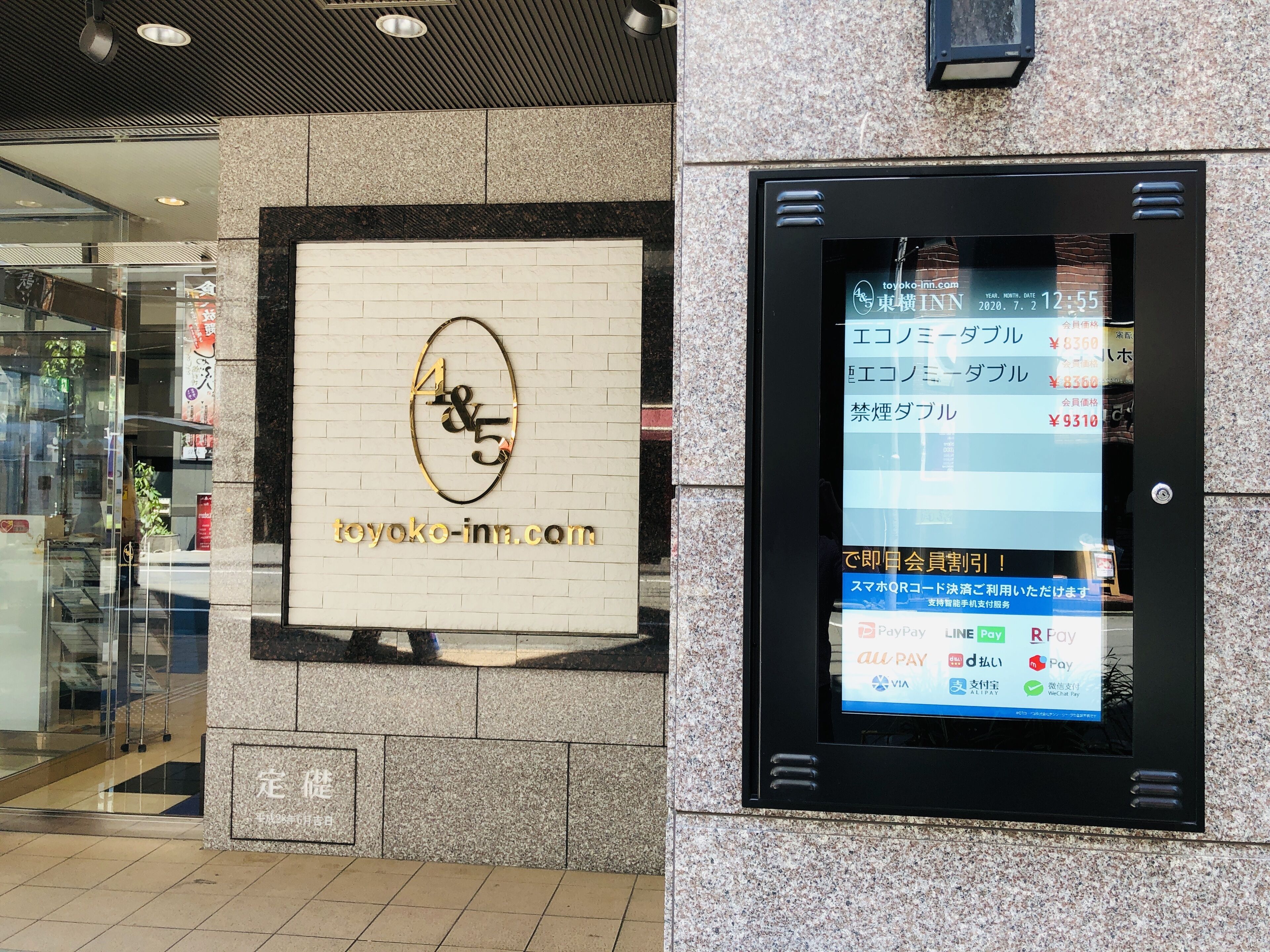 A hotel sign with the name 'toyoko-inn.com' and a digital display showing room rates.