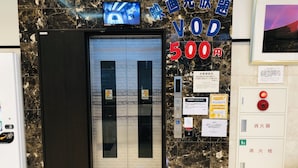 An elevator entrance with a digital display, a sign indicating a 500 yen charge, and various informational notices. - Toyoko Inn Tokyo Hachioji Station Kita (Hachioji)