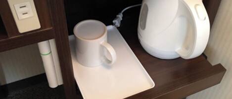 A coffee maker and a mug on a tray in a hotel room.