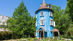 A blue tower house with a conical roof, surrounded by lush greenery and a garden with various plants. - Toyoko Inn Tokyo Seibu Ikebukuro Line Higashi Kurume Station Nishi (Higashikurume)