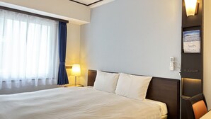 A hotel room with a large bed, a bedside table with a lamp, a wall-mounted phone, and a picture frame. - Toyoko Inn Tokyo Seibu Ikebukuro Line Higashi Kurume Station Nishi (Higashikurume)