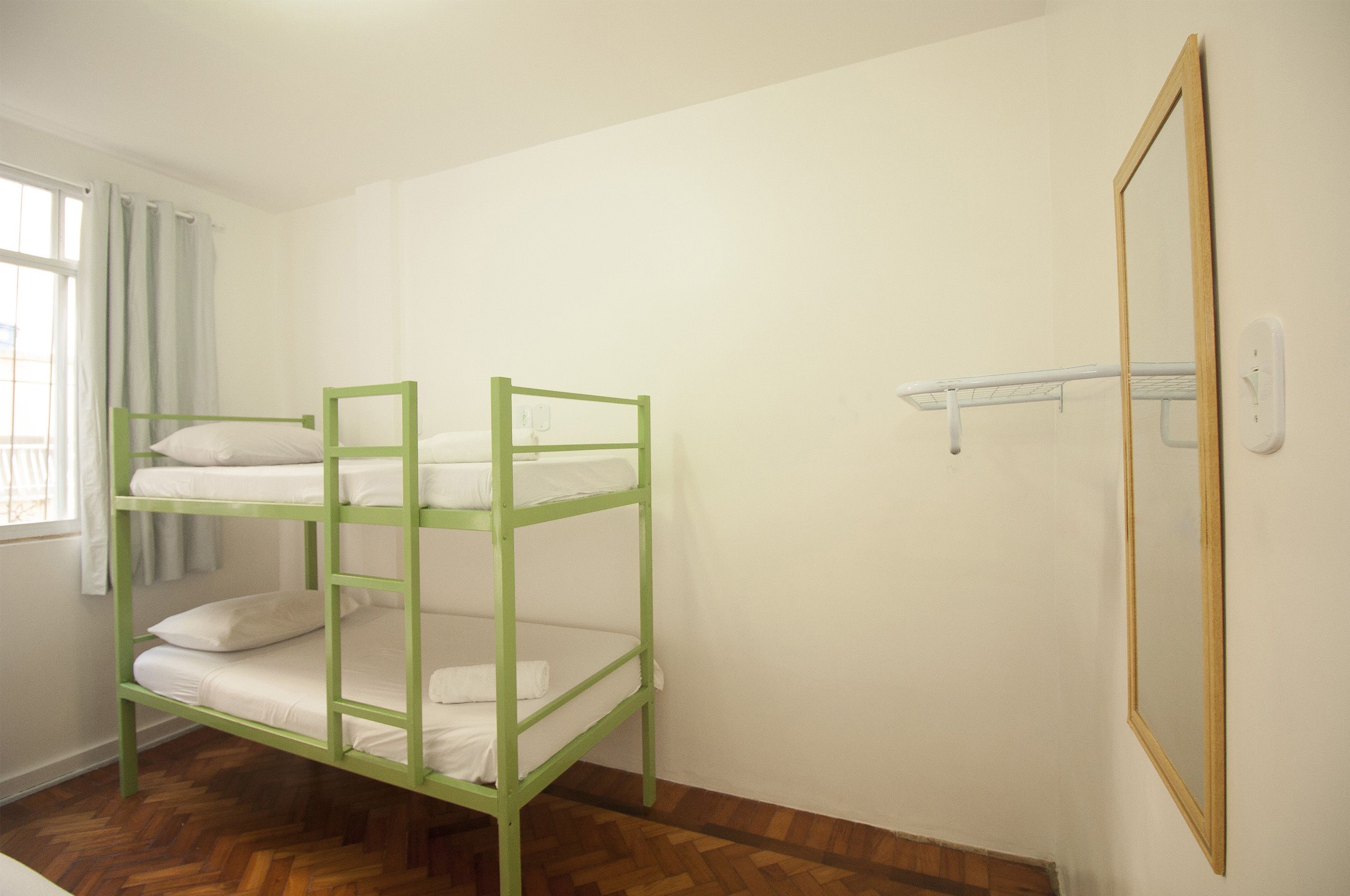 A bunk bed room with white bedding and a wooden frame.