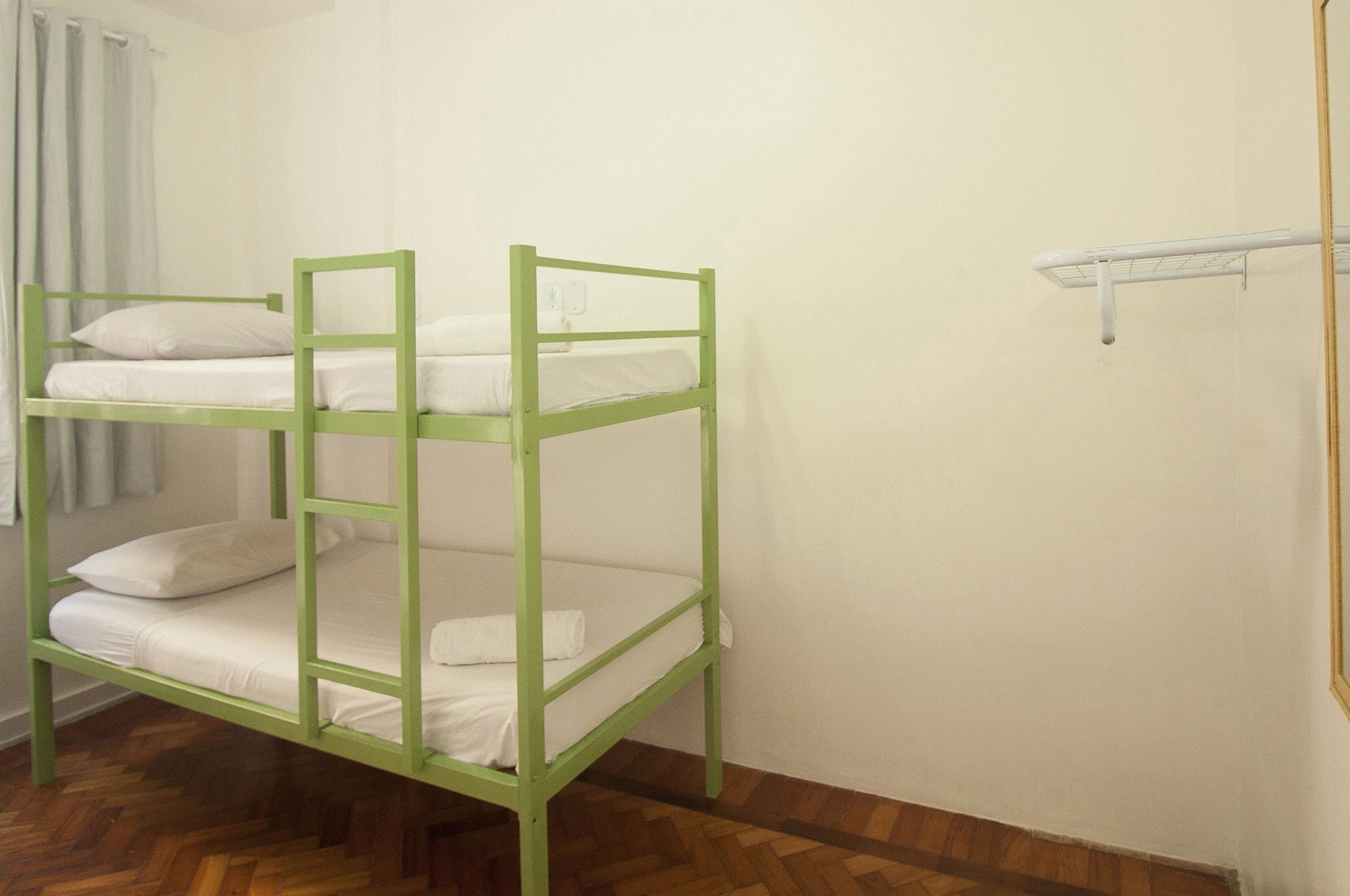 Una cama litera con ropa blanca y suelo de madera.