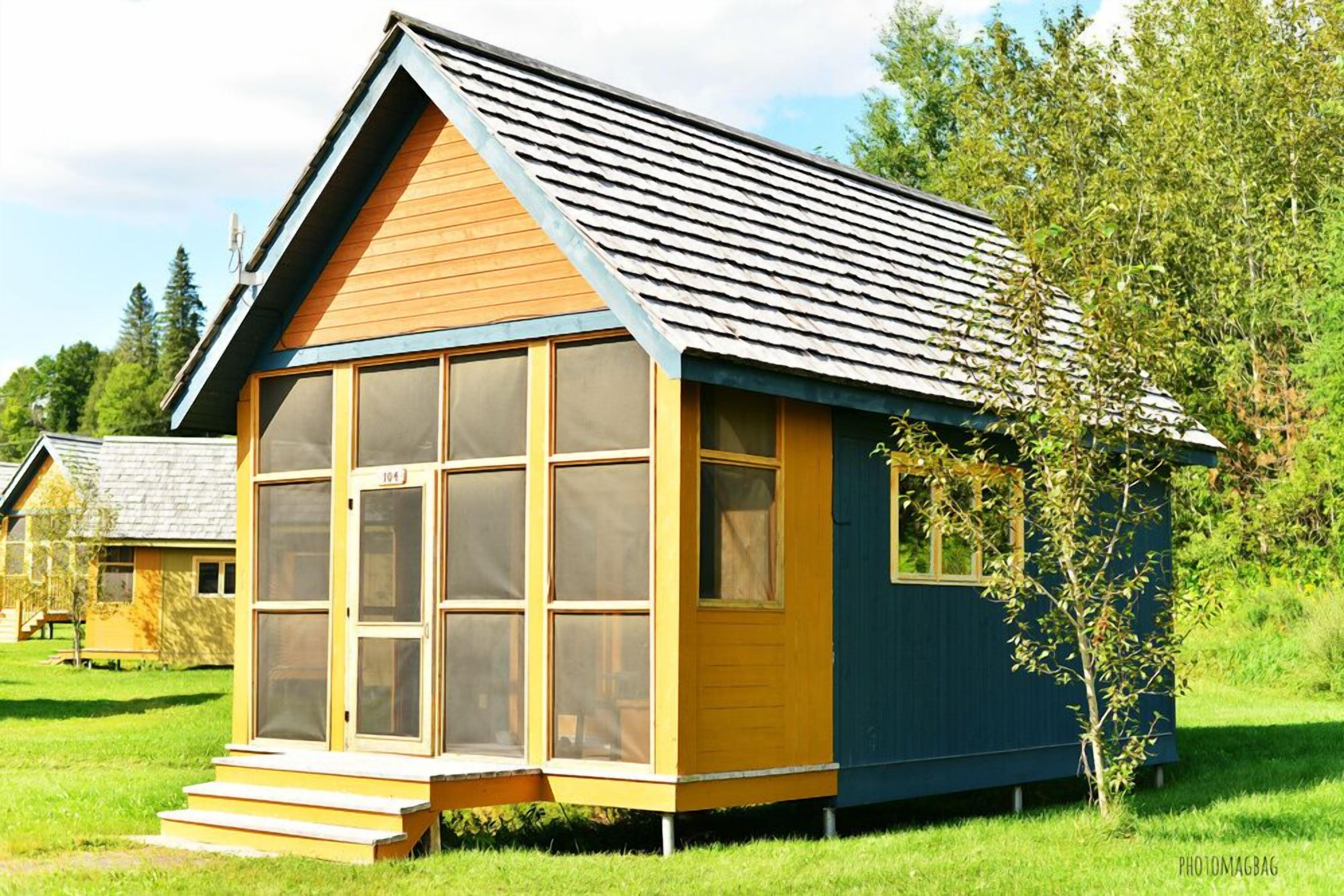 A small, single-story cabin with a sloped roof, large windows, and a wooden exterior.