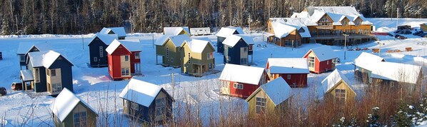 Un groupe de cabanes nichées dans un paysage enneigé, avec une forêt en arrière-plan.