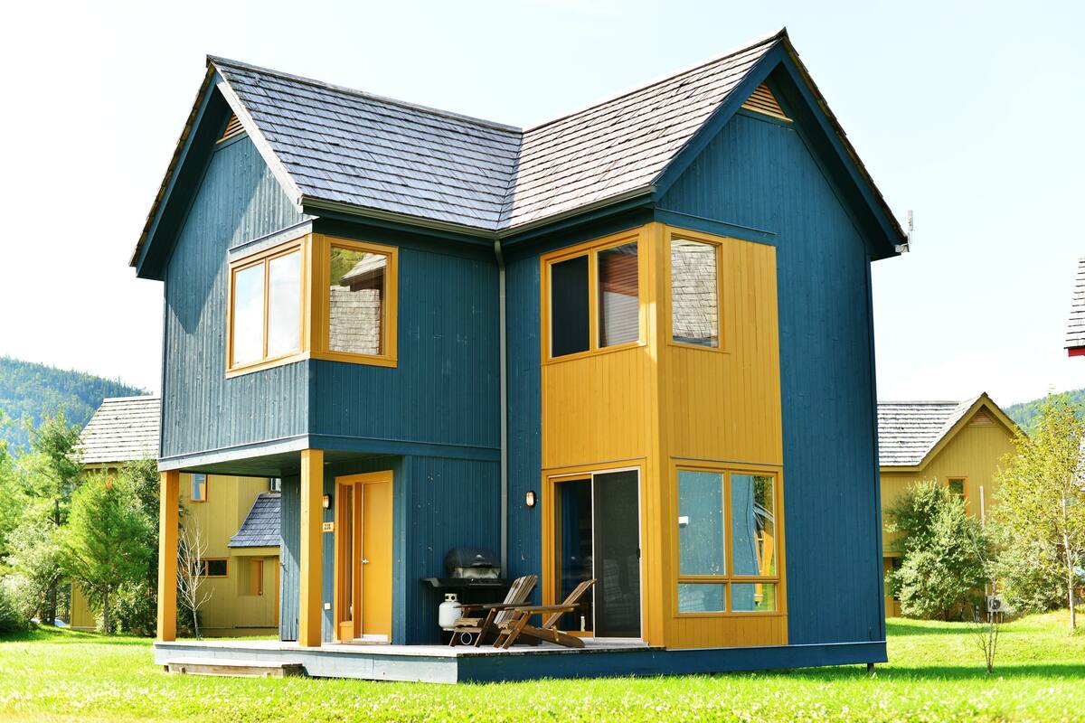 A two-story house with a porch, a barbecue area, and a large window.