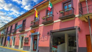 Un bâtiment rose doté de balcons, une enseigne indiquant un hôtel et des drapeaux.