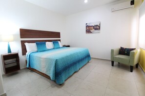Ein Schlafzimmer mit einem Bett, Nachttischen, einem Sessel und einer Wand-Klimaanlage.
