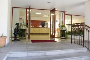 A hotel lobby with a reception desk, a staircase leading to the upper floor, and potted plants. - Casa de la iaia Hotel (Orizaba)