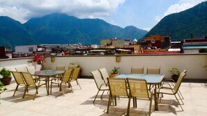 Une terrasse extérieure avec une table et des chaises en verre, entourée de plantes en pot.