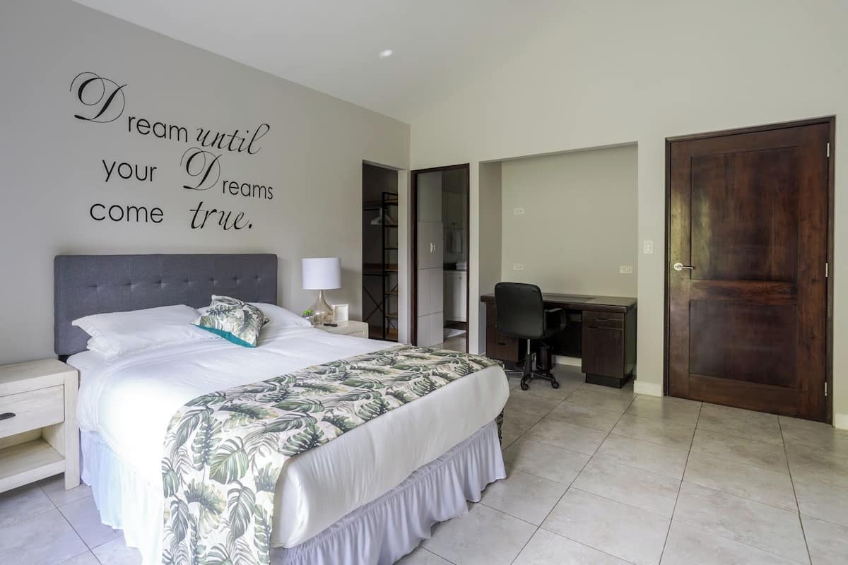 A bedroom with a bed, a desk, and a wardrobe.