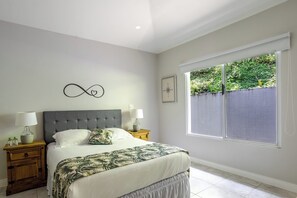 A bedroom with a bed, nightstands, a window with a view, and a wall with a compass and infinity symbol. - Coffee Estate Inn (Jaramillo)
