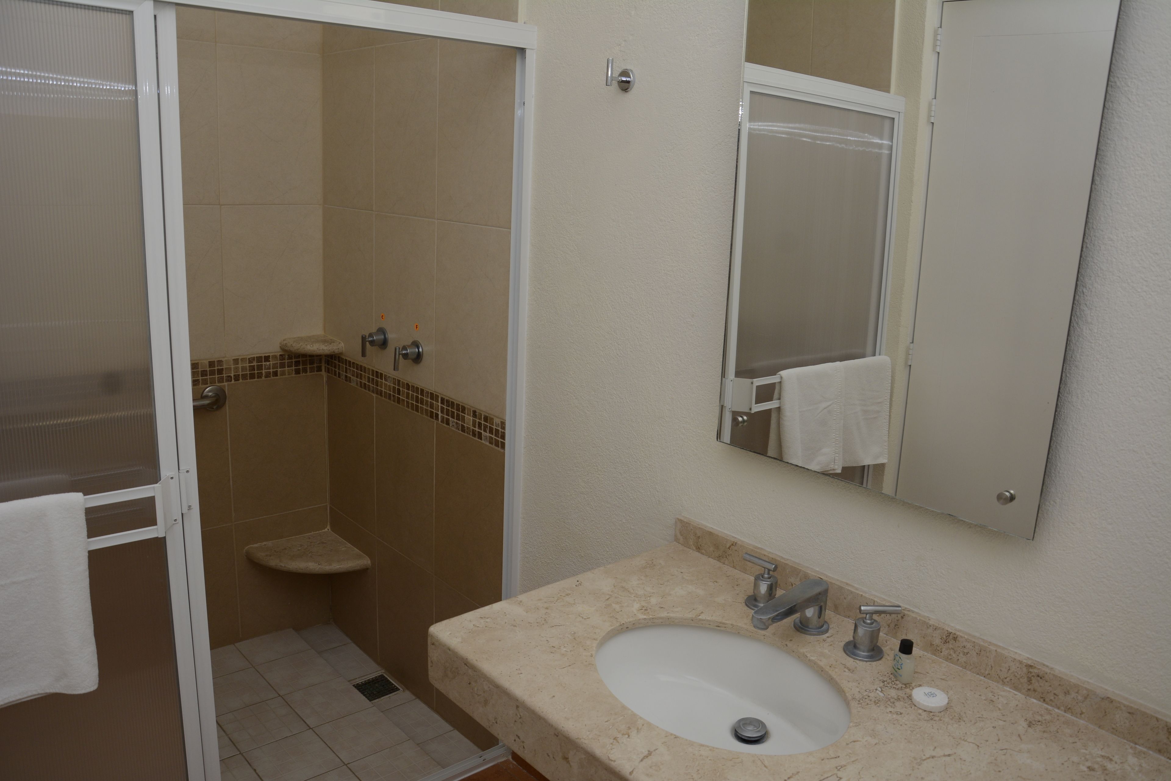 A bathroom with a sink, mirror, and shower.
