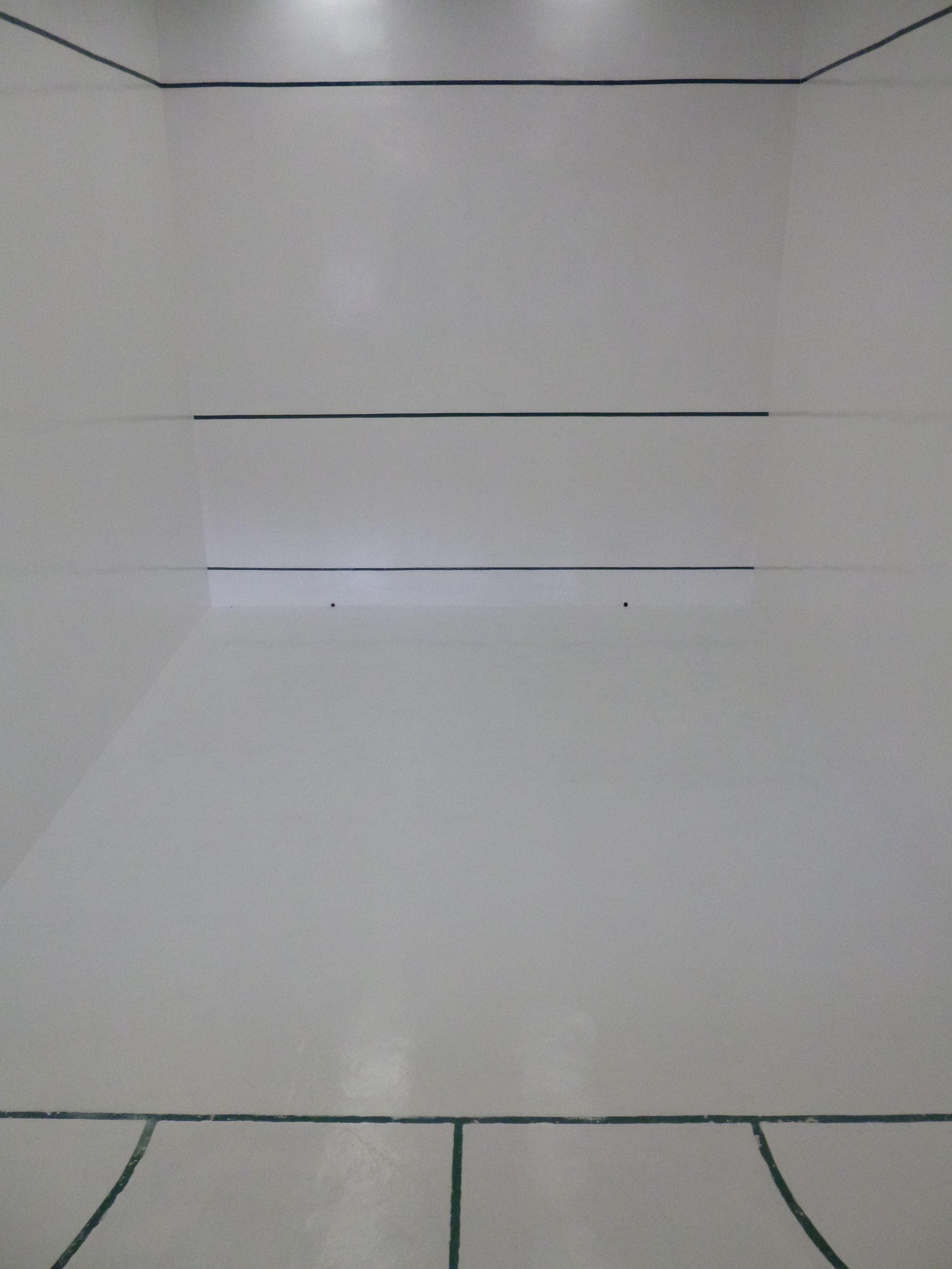 Una habitación con una pared blanca lisa y piso de baldosas.