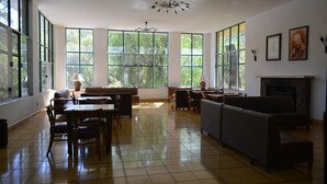 A spacious room with large windows, a fireplace, and a dining area with chairs and tables. - Lourdes Hotel Campestre (Santa Maria del Rio)