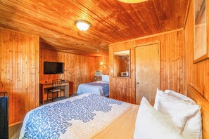 A wooden cabin room with two beds, a desk, a television, and a mirror. - Green Acre Motel by OYO Near Rush County Airport (La Crosse)
