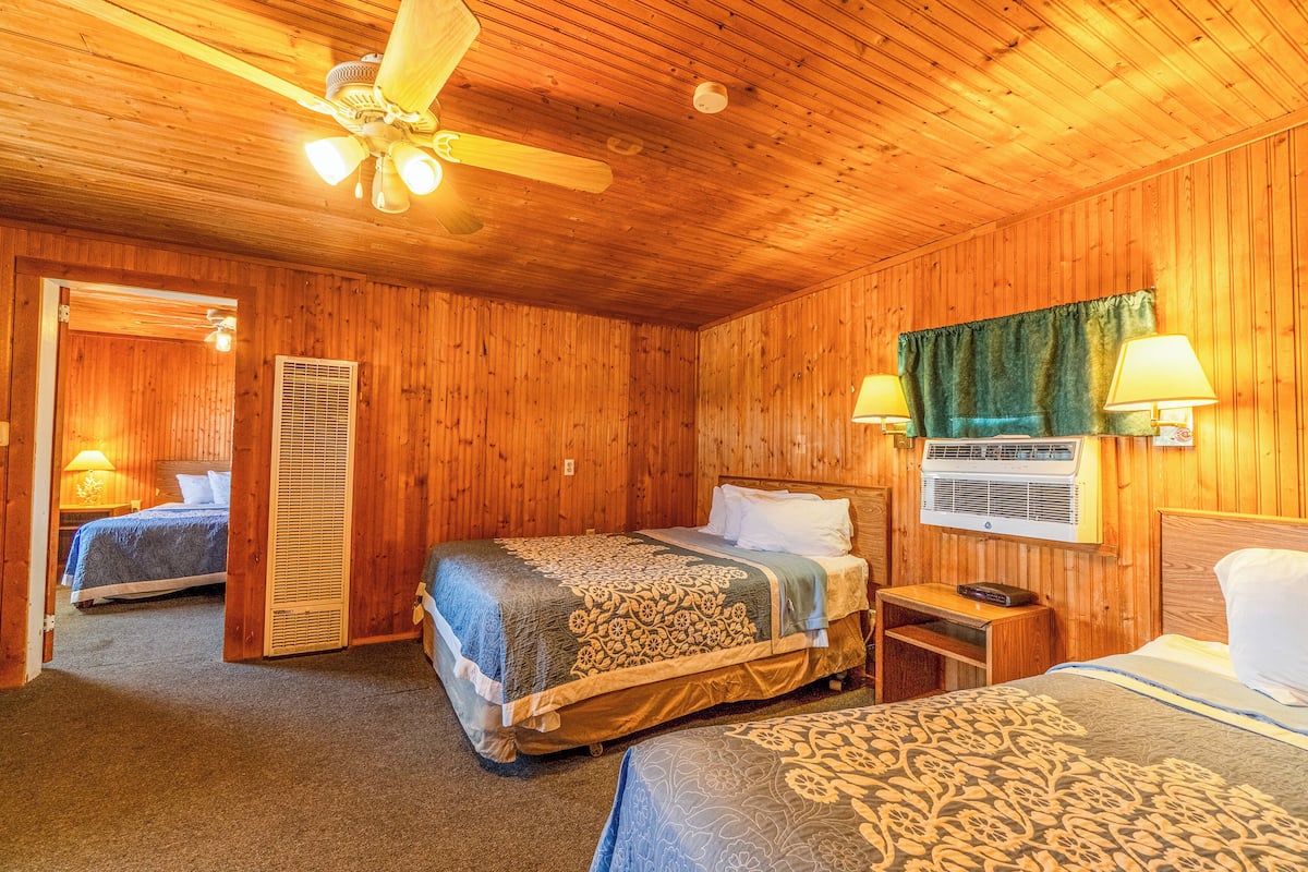Dormitorio de cabaña de madera con dos camas, ventilador de techo y aire acondicionado.