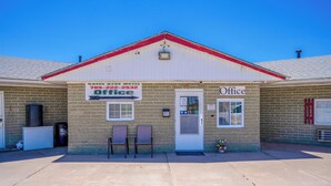 A brick building with a white door and a sign that reads "Green Acres Motel Office." - Green Acre Motel by OYO Near Rush County Airport (La Crosse)
