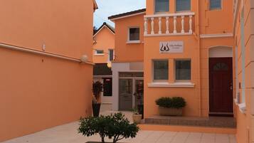 A narrow street with buildings painted in a warm orange hue. There is a sign for 'Villa Antibes L'Annexe' on one of the buildings.