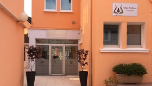 A hotel entrance with a reception sign, a reception desk, and two potted plants. - Résidence Chez Gino (Etaples)