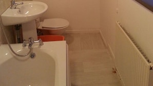A bathroom with a bathtub, sink, and toilet. - Icon Harwich Apartment (Harwich)