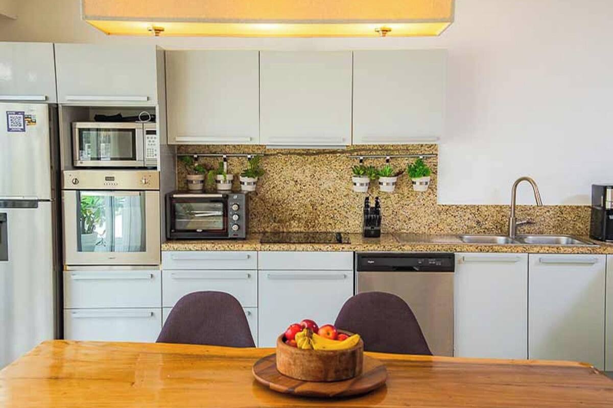Een moderne keuken met inbouwapparatuur, een granieten aanrechtblad en potplanten.