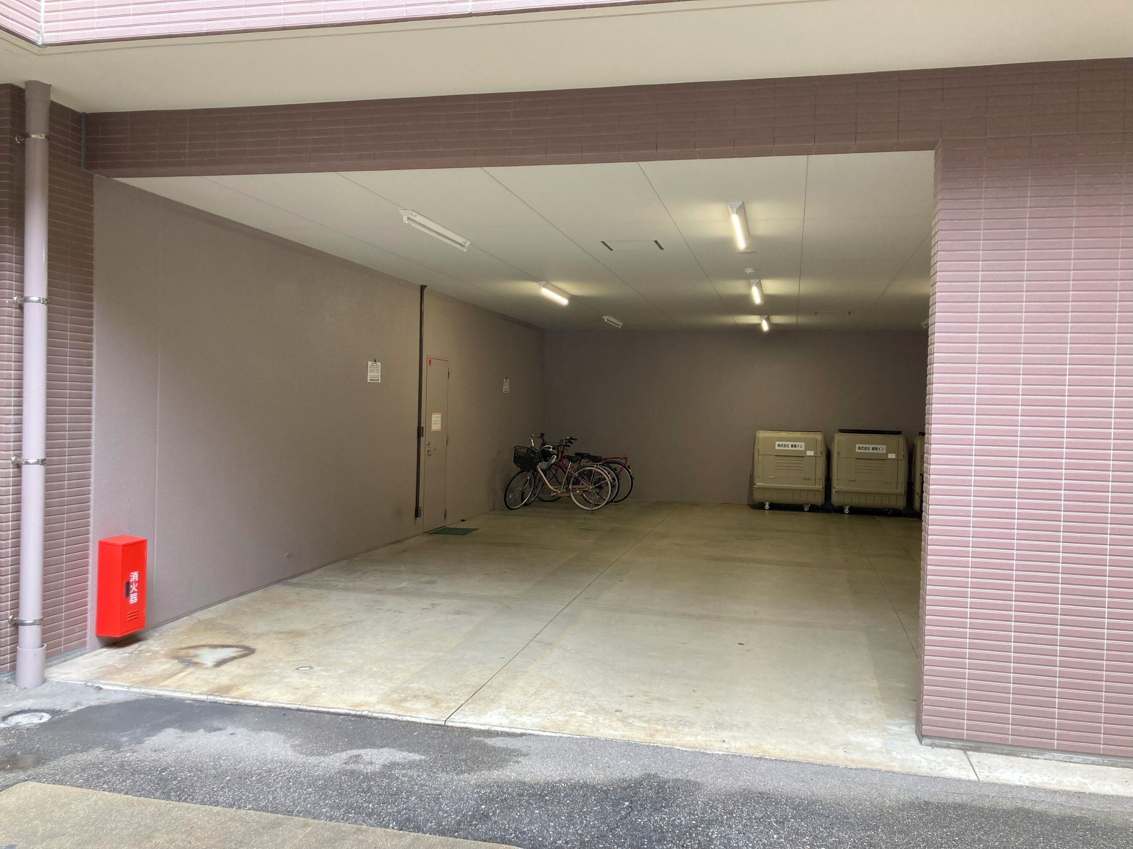 Un garaje de estacionamiento con piso de concreto, una bicicleta y dos bodegas.