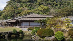 A traditional Japanese building with a tiled roof, surrounded by a pond and lush greenery. - Toyoko Inn Kagoshima Chuo Station Higashi (Kagoshima)