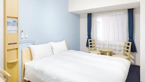 A hotel room with a large bed, two chairs, a small table, and a window with curtains. - Toyoko Inn Kagoshima Chuo Station Higashi (Kagoshima)