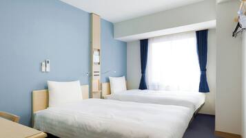 A hotel room with two beds, a bedside table, a nightstand, a window with curtains, and a ceiling light.