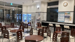 A modern indoor seating area with tables and chairs, vending machines, and a clock on the wall. - Toyoko Inn Tsuruga Ekimae (Tsuruga)