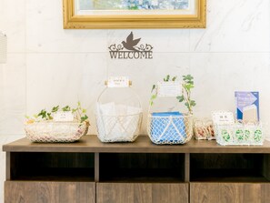 A reception desk with a 'WELCOME' sign, various baskets with labels, and a framed picture on the wall. - Toyoko Inn Tsuruga Ekimae (Tsuruga)