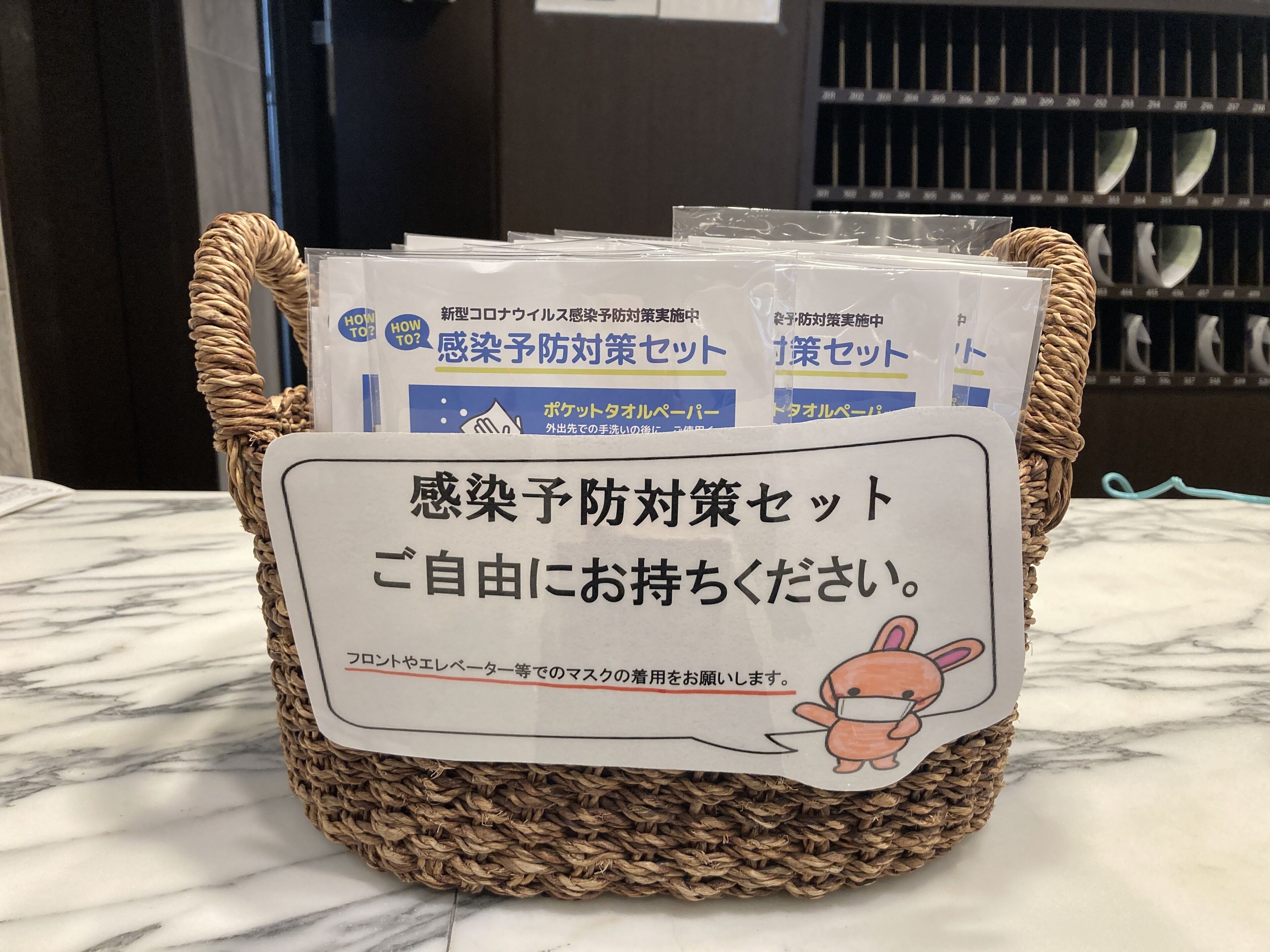 A woven basket containing pamphlets with Japanese text, placed on a marble surface.