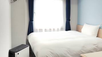 A hotel room with a bed, a desk, and a window with curtains.