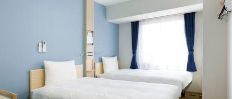 Habitación de hotel con dos camas, un escritorio, un espejo y una ventana con cortinas.