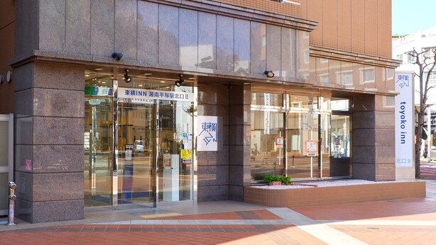 A building with a glass entrance, signage in a foreign language, and a small planter with plants. - Toyoko Inn Shonan Hiratsuka Station Kita 2 (Hiratsuka)