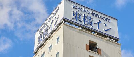 Un bâtiment sur lequel on peut lire l’inscription « toyoko inn.com » et « 東横イン » en anglais et en japonais.