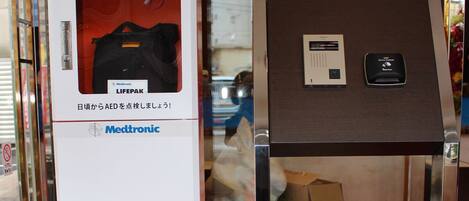 Un desfibrilador automático externo y un panel de control sobre una mesa en un espacio público.