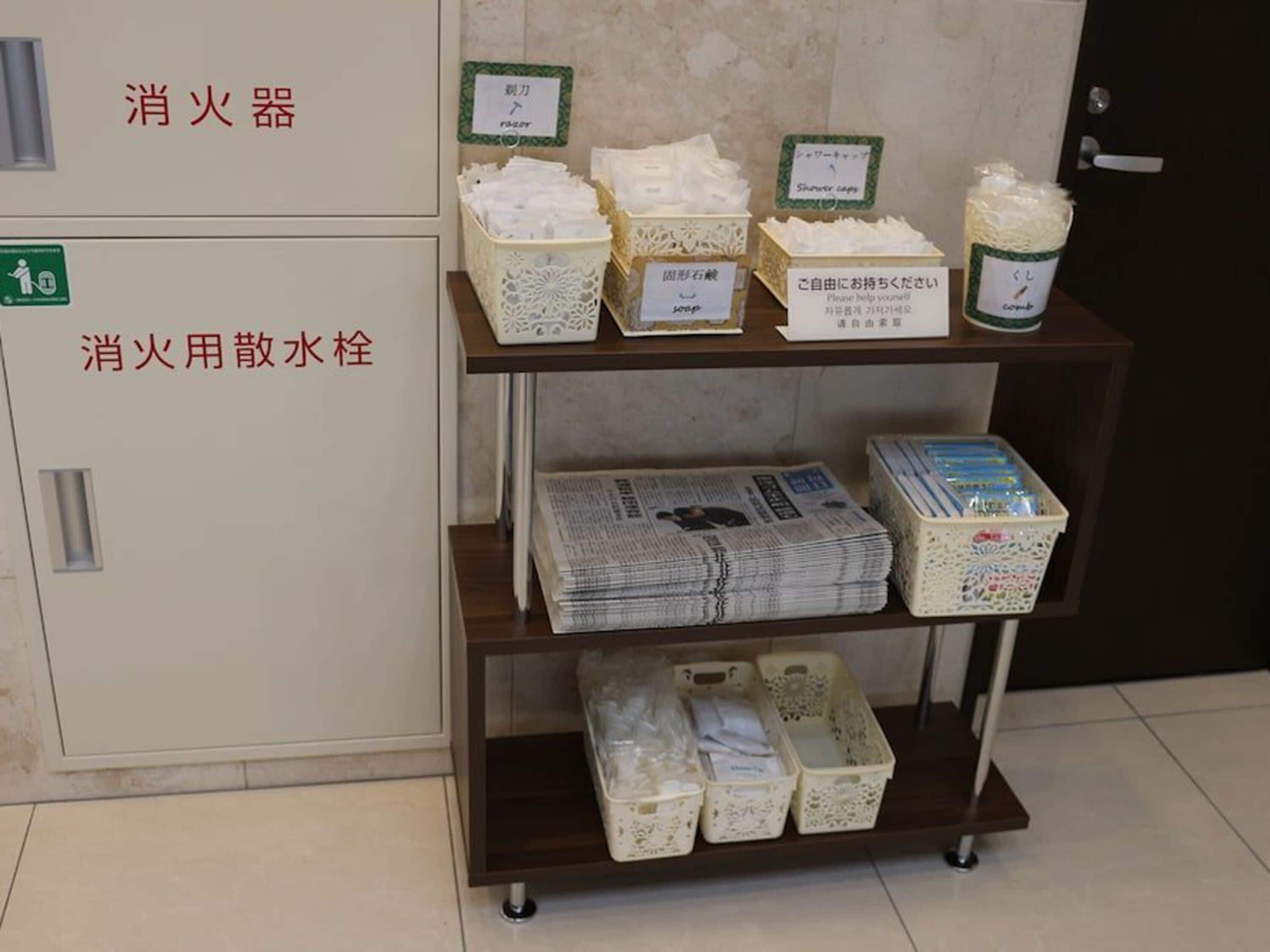 A shelf with various items including a fire extinguisher, a first aid kit, and newspapers.
