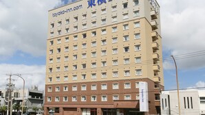 A multi-story hotel with a beige facade, multiple windows, and a sign reading "toyoko inn". - Toyoko Inn Okinawa Ishigaki jima (Ishigaki)