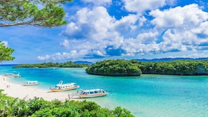 A tropical beach with clear turquoise waters, boats, and lush greenery. - Toyoko Inn Okinawa Ishigaki jima (Ishigaki)