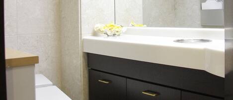 A bathroom with a white toilet, a sink with a white countertop, and a dark cabinet below.