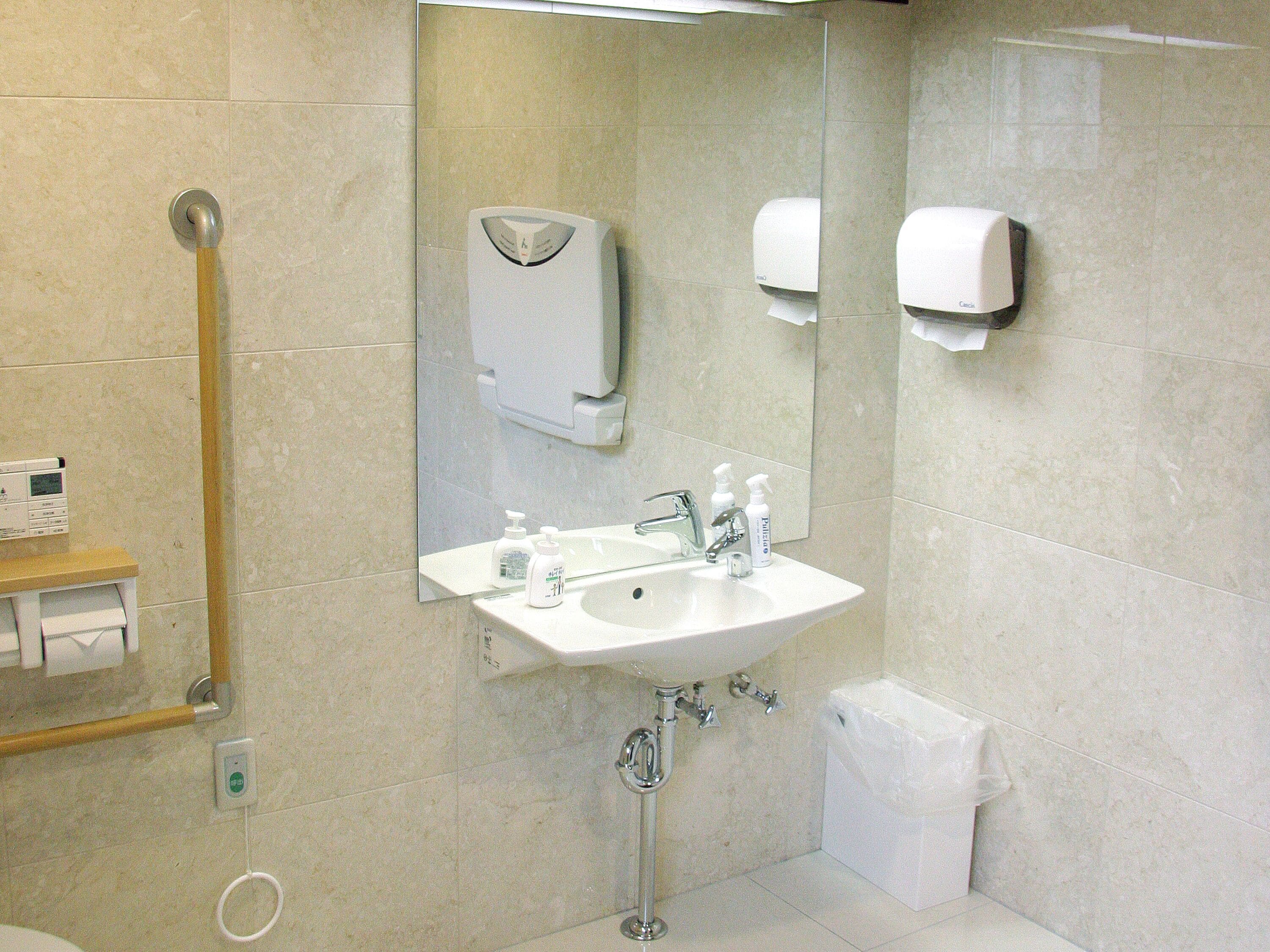 Une salle de bain équipée d’un lavabo, d’un miroir, d’un sèche-mains et d’un distributeur de serviettes en papier.